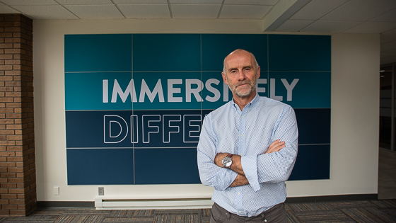 photo of andrew wood standing in front of a sign that reads Immersively Different